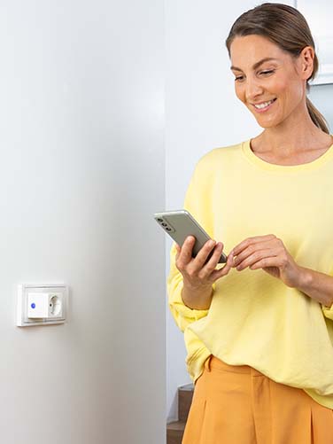 Apple Home Person bedient eingesteckte HomeKit-Steckdose mittels Apple Home-App.