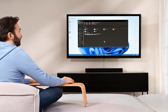Person sitzt auf Sofa und schaut auf Fernseher, der als Monitor dient
