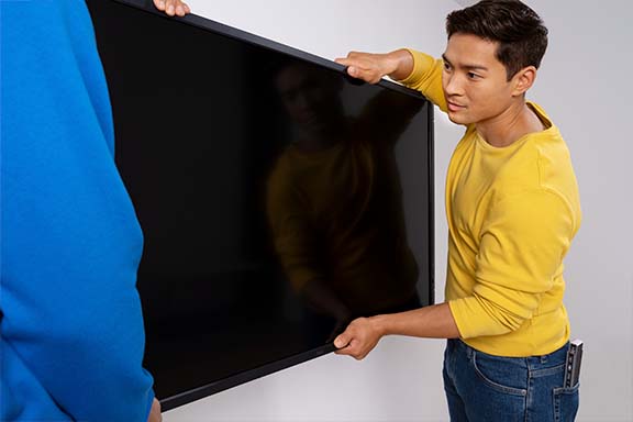 Person bringt Fernseher an TV-Wandhalterung an