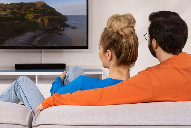 Mann und Frau kuscheln auf einem Sofa und schauen Fernsehen.