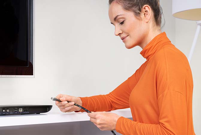 Person schließt ein Koaxialkabel am Receiver an.
