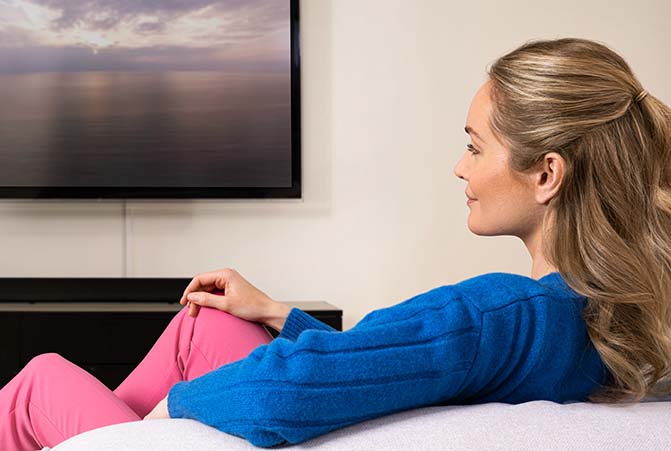 Person sitzt auf dem Sofa vor dem Fernseher