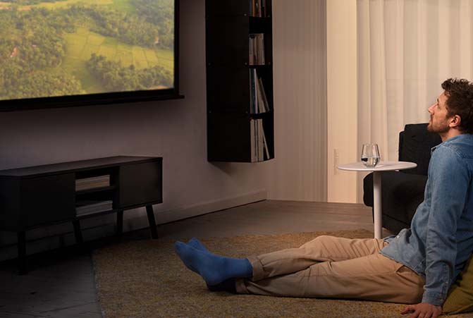 Person schaut einen Film über einen Beamer an der Wand