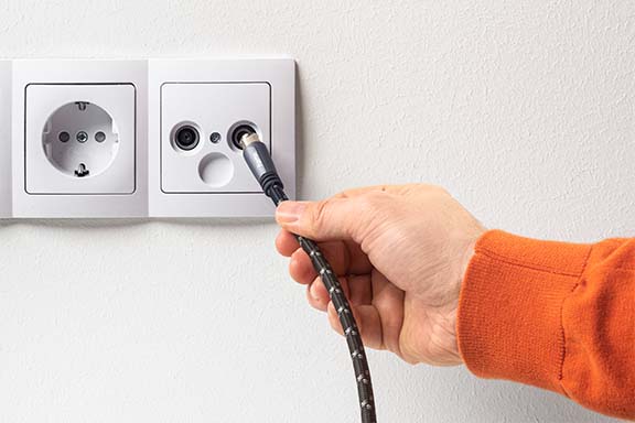 Hand mit Antennenkabel an Kabelfernsehen-Dose