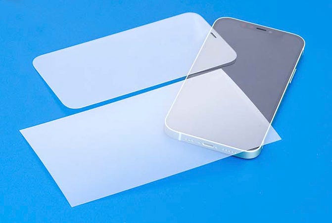 Hama Displayschutzfolie und Panzerglas liegen auf einem blauen Tisch über einem Smartphone