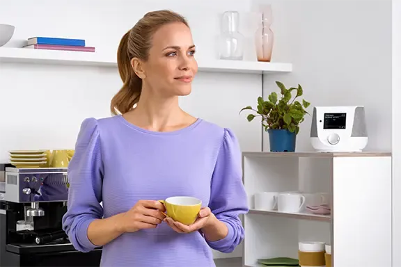 Frau steht in der Küche mit Hama Digitalradio im Hintergrund