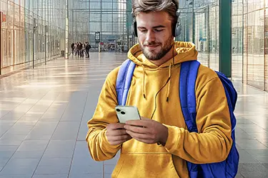 Mann in einer Halle benutzt sein Handy mit Kabelkopfhörern