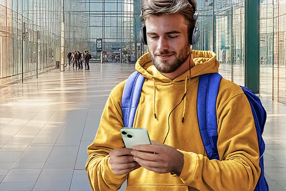 Mann in einer Halle benutzt sein Handy mit Kabelkopfhörern
