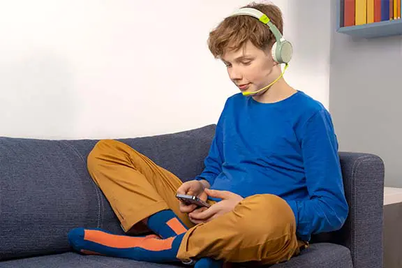 Kind mit Kinderkopfhörern von Hama auf der Couch