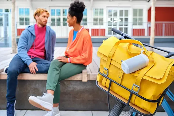 Weißer Bluetooth-Lautsprecher auf einer gelbem Tasche im Freien