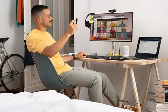Mann sitzt an einem Schreibtisch und nimmt an einem Online-Meeting teil