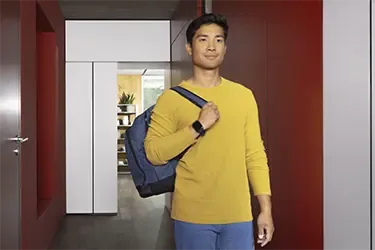 Mann läuft mit Rucksack durch den Flur und hat eine Smartwatch von Hama am Handgelenk