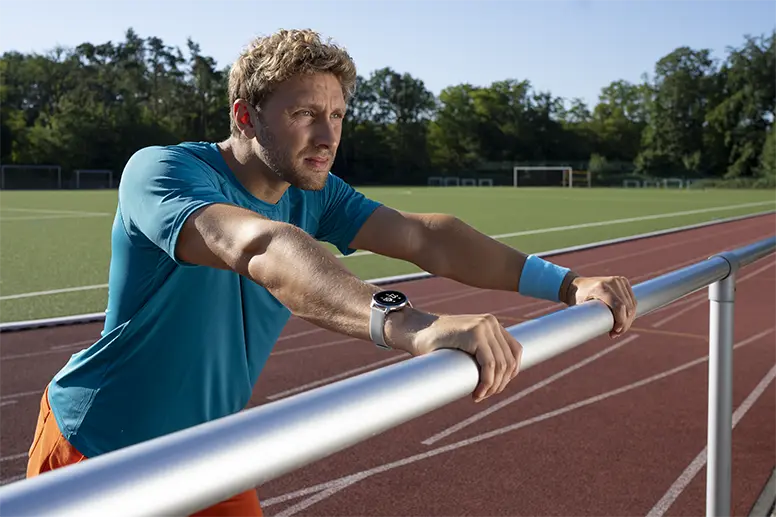 Mann lehnt an Geländer an einem Sportplatz mit einer Smartwatch von Hama