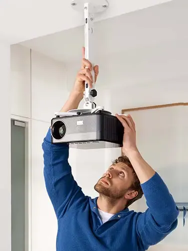 Person stellt einen höhenverstellbaren Beamer ein