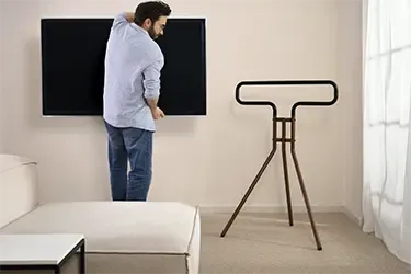 Fernseher wird an TV-Ständer montiert.