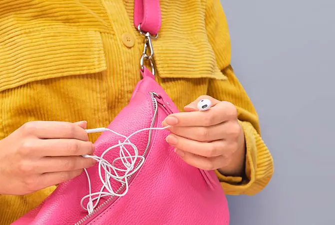 Person packt verknotete Kabel-Kopfhörer aus.