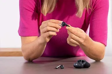 Frau reinigt mit einem Tuch ihre schwarzen Earbuds