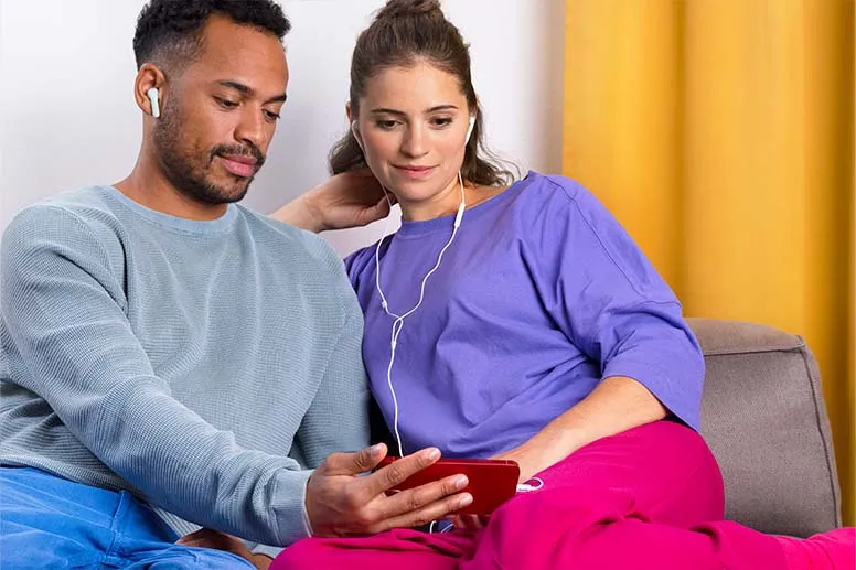 Paar verwendet verschiedene Kopfhörer, um sich auf dem Smartphone etwas anzusehen
