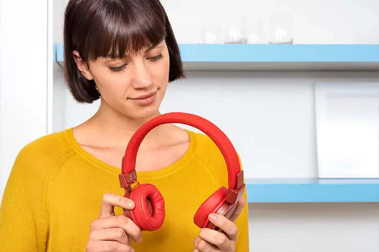 Rote Over-Ear-Kopfhörer Frau in gelbem Oberteil hat rote Over-Ear-Kopfhörer in der Hand