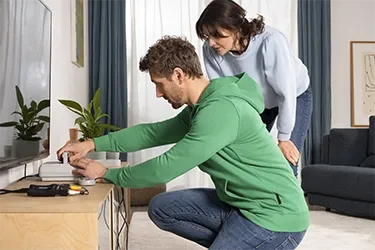 Person schließt Konsole an den Fernseher an.