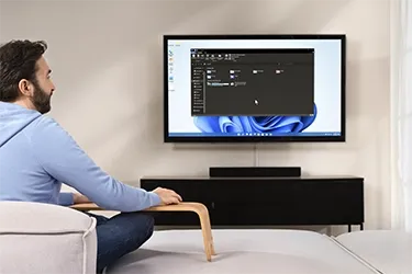 Person sitzt auf Sofa und schaut auf Fernseher, der als Monitor dient
