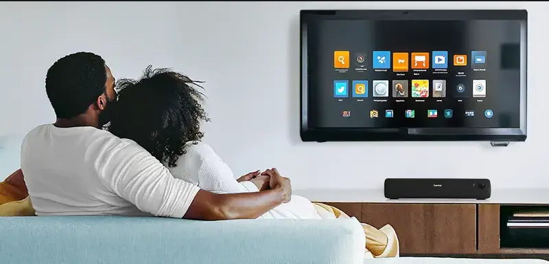Päärchen sitzt auf einem blauen Sofa vor einem nachgerüsteten Smart TV