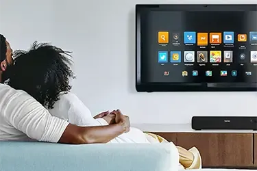 Päärchen sitzt auf einem blauen Sofa vor einem nachgerüsteten Smart TV
