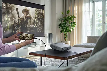 Person hält Handy in der Hand und überträgt Serie von Handy über Beamer an Leinwand mittels Kabel