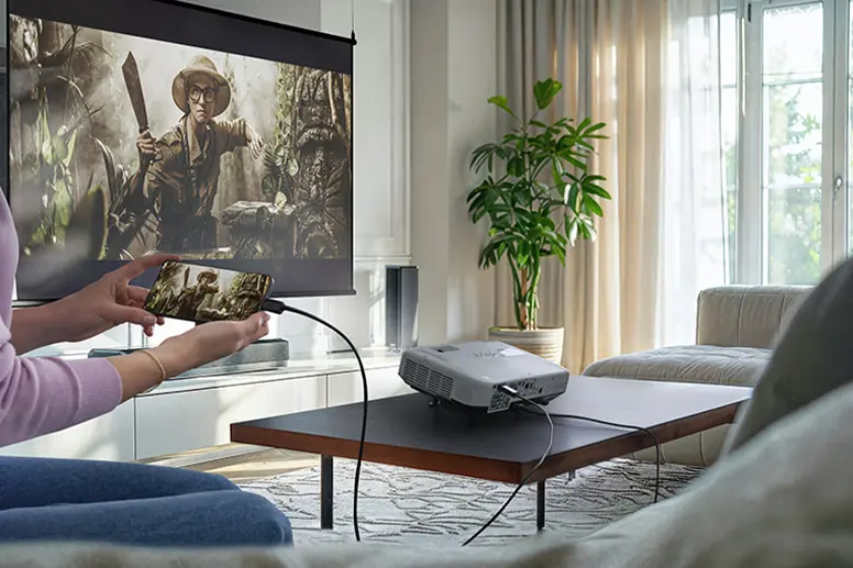Person hält Handy in der Hand und überträgt Serie von Handy über Beamer an Leinwand mittels Kabel