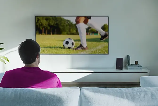 Person sitzt auf dem Sofa und schaut TV, kein Kabel ist sichtbar