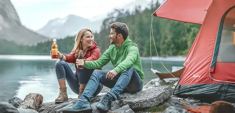 2 Personen sitzen vor einem Camper am See
