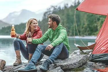 2 Personen sitzen vor einem Camper am See