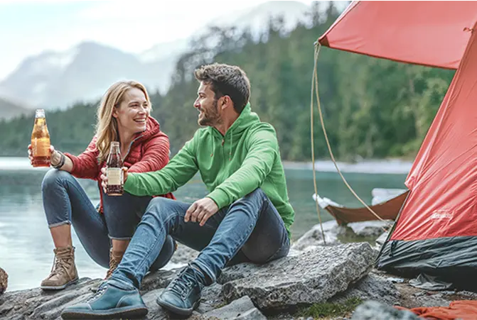 Personen sitzen vor einem Zelt am See