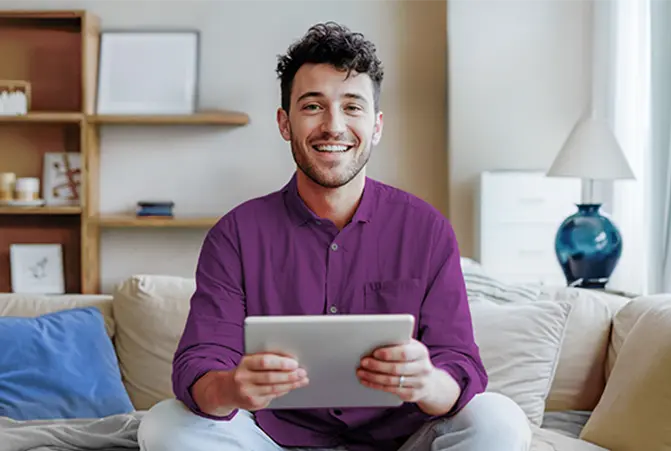 Person sitzt mit dem Tablet auf dem Sofa.