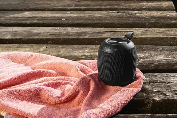Tragbarer Bluetooth-Lautsprecher steht auf einem Handtuch an einem Steg