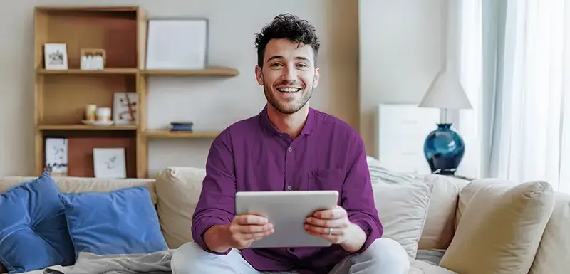 Person sitzt mit dem Tablet auf dem Sofa.