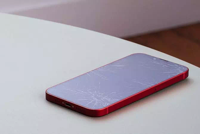 iPhone mit verkratzter Schutzfolie liegt auf einem abgerundeten Tisch