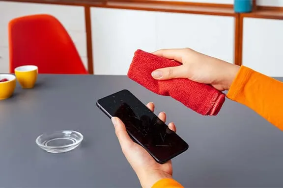 Handy-Display wird mit rotem Mikrofasertuch gereinigt
