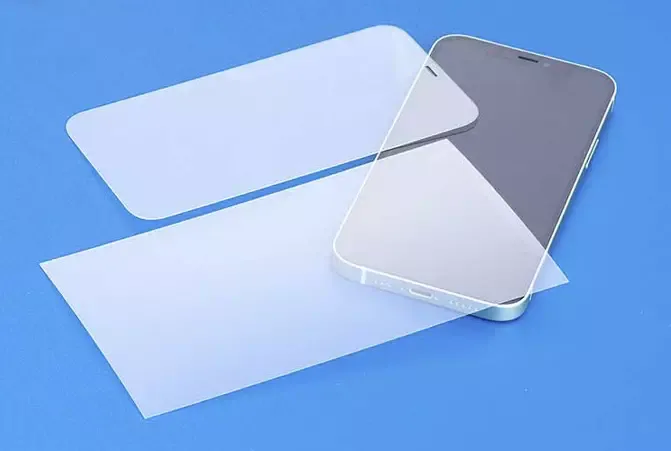 Hama Displayschutzfolie und Panzerglas liegen auf einem blauen Tisch über einem Smartphone