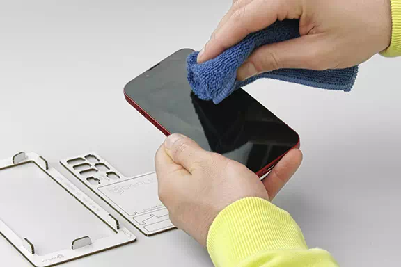 Smartphone wird in der Hand gehalten und mit einem Mikrofasertuch gereinigt