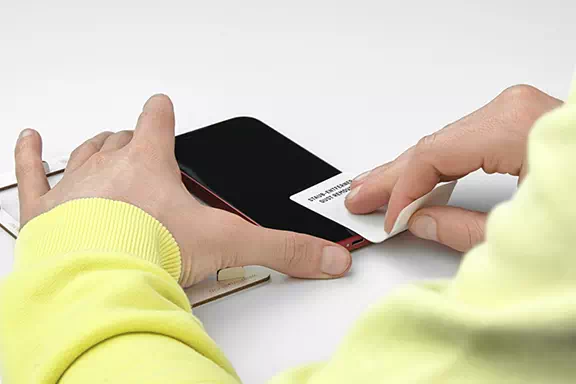 Staubkörner auf dem Handy-Display werden mithilfe eines Klebe-Stickers entfernt