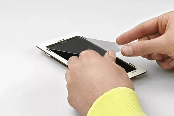 Panzerglas wird mit beiden Händen auf dem Handy-Display positioniert