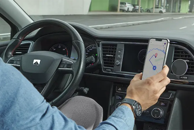 Autofahrer justiert ein Handy, das in einer Halterung fixiert ist und eine Navigations-App anzeigt