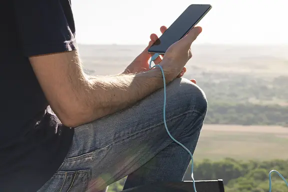 Mann mit Handy in der Hand und Ladekabel.