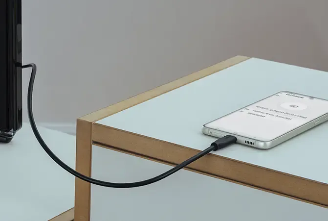 Smartphone ist mit Kabel an Fernseher angeschlossen