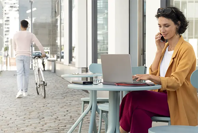 Person sitzt im Cafe und arbeitet an einem Laptop der an eine Powerbank angeschlossen ist.