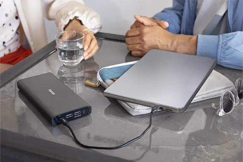 Effiziente Laptop-Aufladung mit externer Powerbank – Mobiles Arbeiten ohne Unterbrechung Laptop wird mit externer Hama Powerbank aufgeladen, zeigt tragbare Ladeoptionen und Akkulaufzeitoptimierung