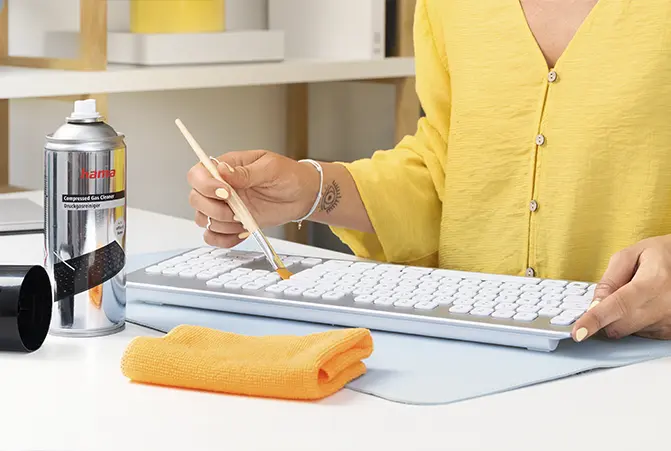 Person reinigt mit Pinsel weiße Hama Tastatur