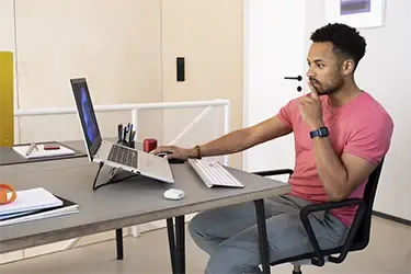 Mann verwendet Laptop mit externem Monitor für effizientes Arbeiten – Tipps zum Anschließen von zwei Monitoren.