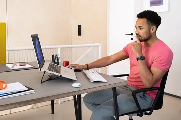 Mann verwendet Laptop mit externem Monitor für effizientes Arbeiten – Tipps zum Anschließen von zwei Monitoren.
